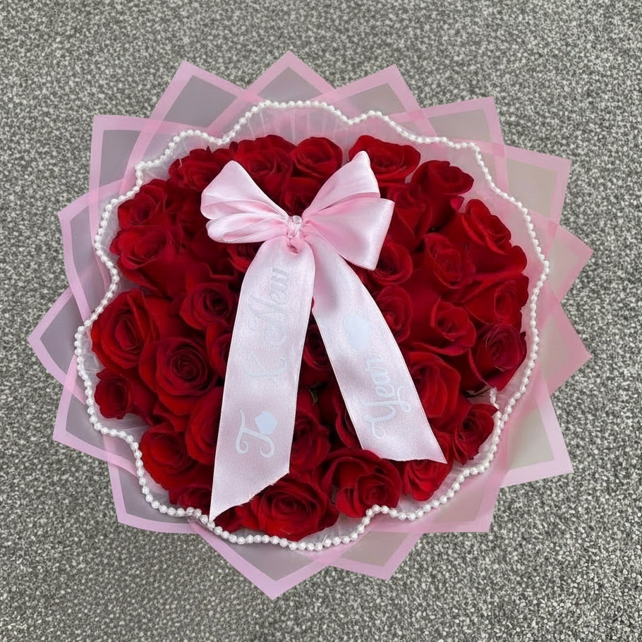Heart-shaped bouquet of red roses with a pink bow