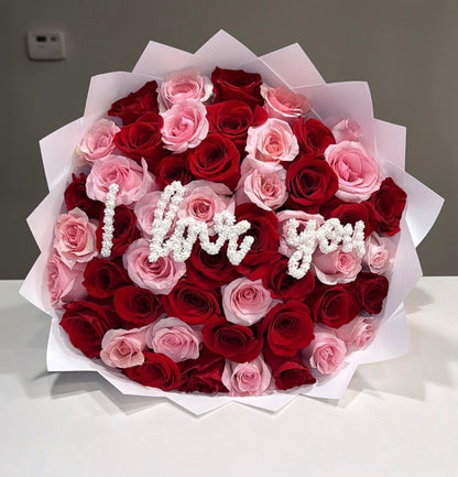 Bouquet of red and pink roses with 'I love you' message on a white background