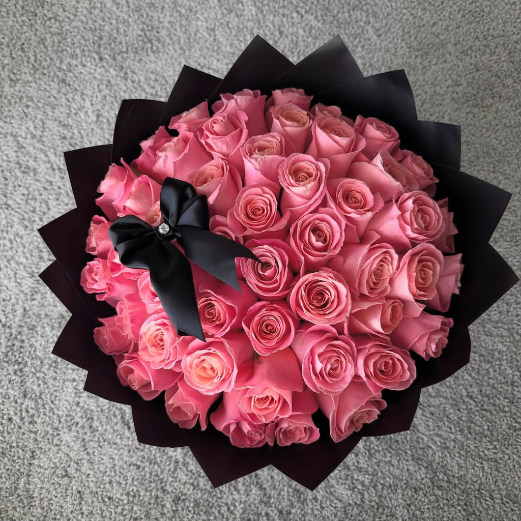 Bouquet of pink roses with a black wrapping papers and a bow 