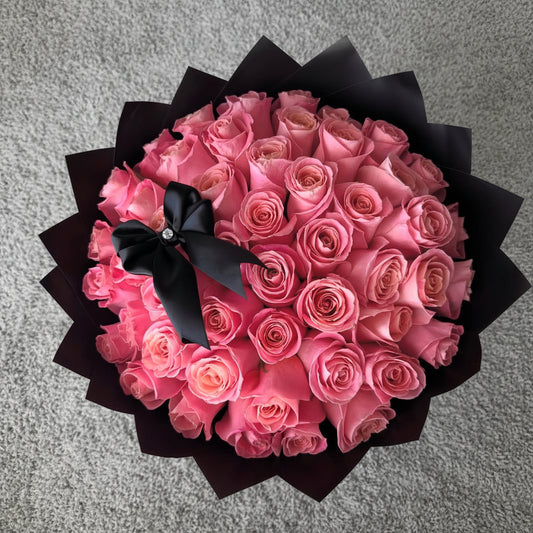Bouquet of pink roses with a black wrapping papers and a bow 
