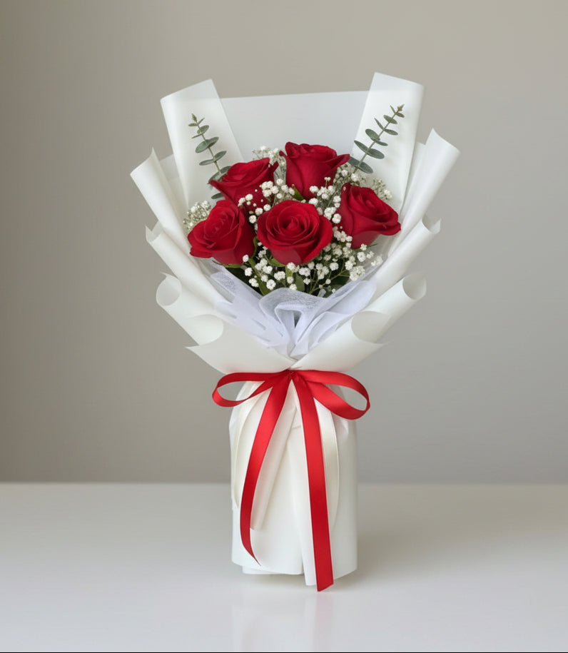 Bouquet of red roses with a white wrap and red ribbon