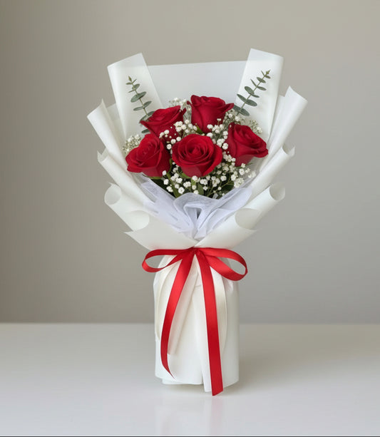 Bouquet of red roses with a white wrap and red ribbon