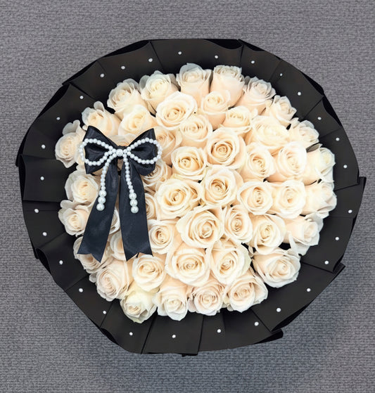 A bouquet of white roses in a wrapped black paper. 
