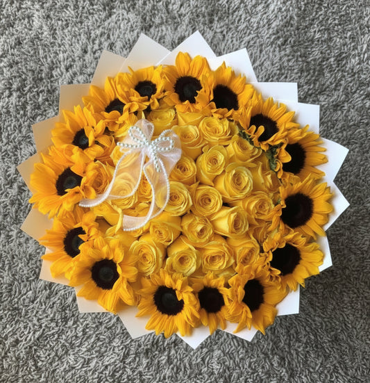 vancouver Bouquet of yellow sunflowers and yellow roses with a white ribbon on a white surface.