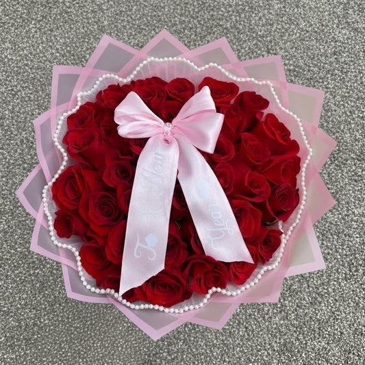 Heart-shaped bouquet of red roses with a pink bow